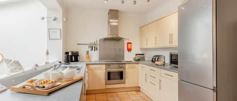 Una cocina moderna con horno empotrado, refrigerador de acero inoxidable y una zona de comedor con una bandeja de comida.