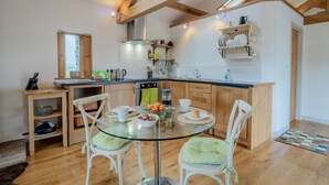 A modern kitchen with wooden beams, a glass dining table, and white cabinetry. - 1 Bed in Shap (oc-t41418) (Shap)