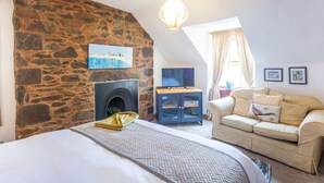 A bedroom with a stone wall, a fireplace, a bed, a sofa, and a television. - 1 Bed in Lauder (oc-83459) (Lauder)