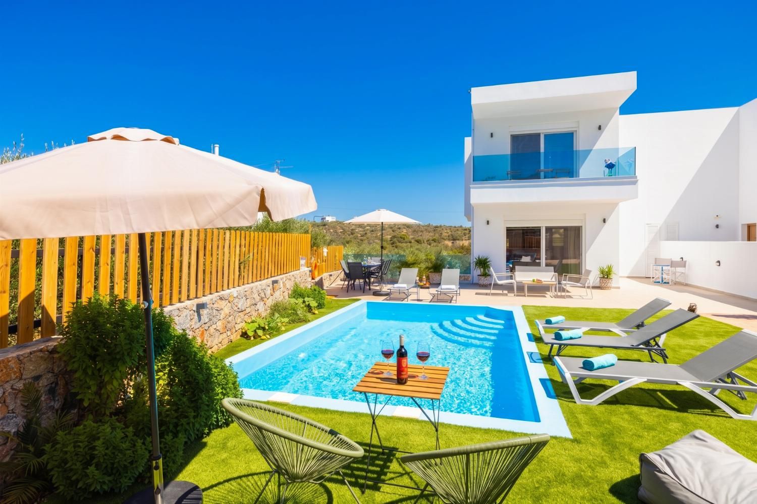 Una villa moderna con piscina, mobiliario exterior y vistas al paisaje.