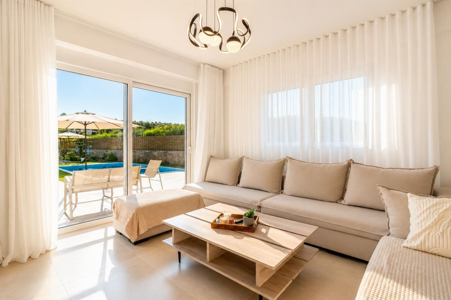 A modern living room with a sofa, coffee table, and a view of a swimming pool.