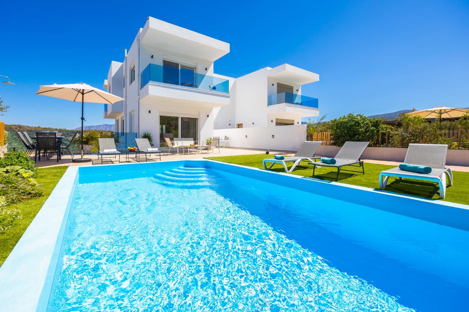 Uma casa moderna de dois andares com piscina, área de estar externa e vista desimpedida da paisagem ao redor.