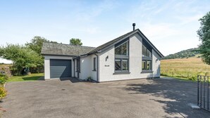 A two-story building with a garage, a driveway, and a rural landscape in the background. - 3 Bed in Penrith (oc-89427) (Hutton)