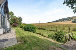 Ein Anwesen mit Terrasse, Sitzgelegenheiten im Freien und Blick auf ein grünes Feld.