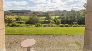 A view through a stone archway with a gravel path and a round table in the foreground. - 12 Bed in Tomatin (oc-ca203) (Woodend)