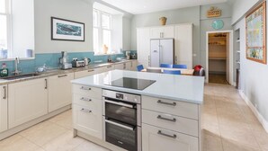 A modern kitchen with a central island, built-in oven, and a refrigerator. - 12 Bed in Tomatin (oc-ca203) (Woodend)