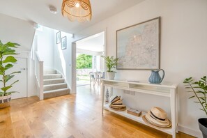 Ein modernes Interieur mit einer Treppe, einem Konsolentisch mit Hüten und einer Karte an der Wand.