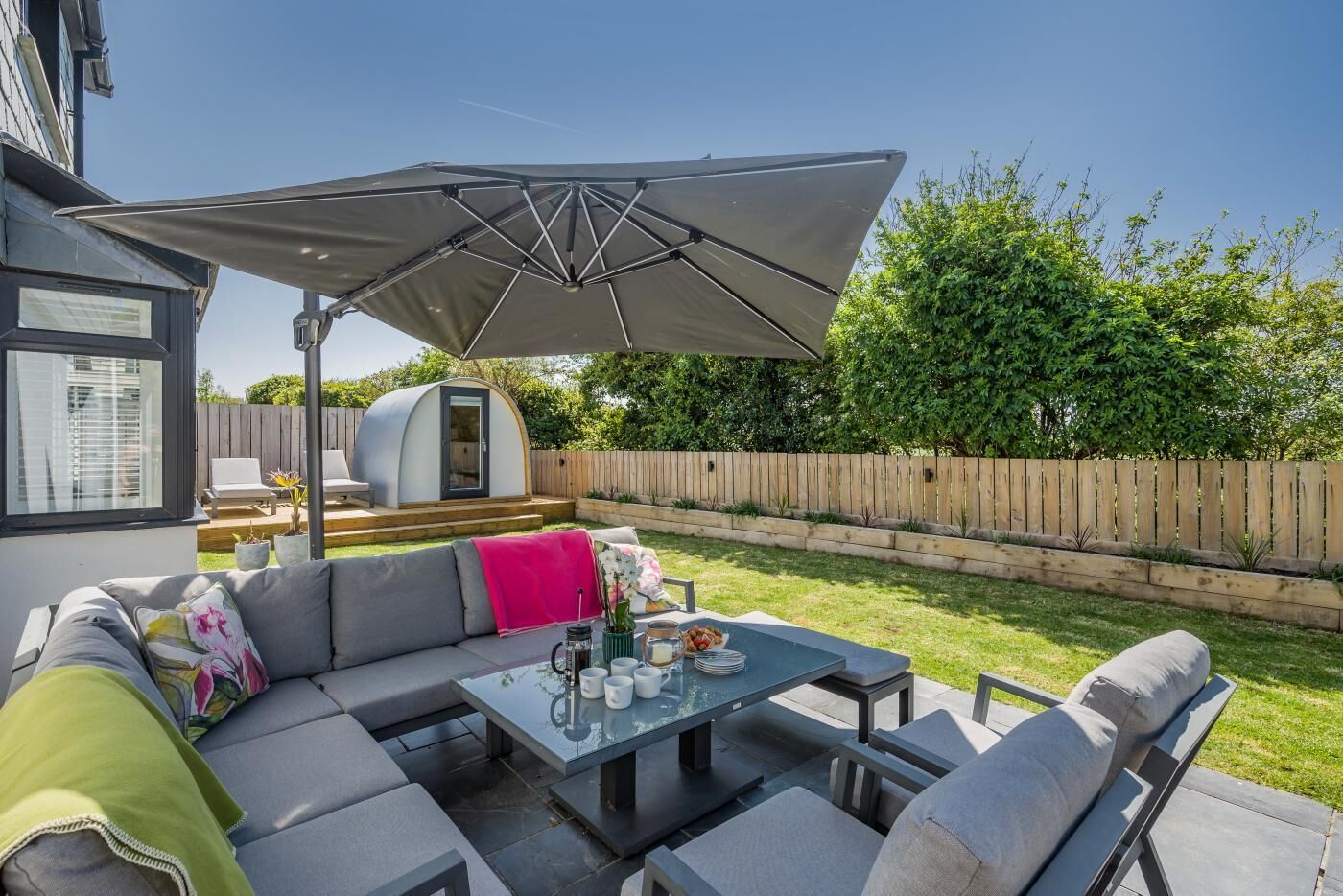 An outdoor patio with a sofa, a table, and an umbrella.