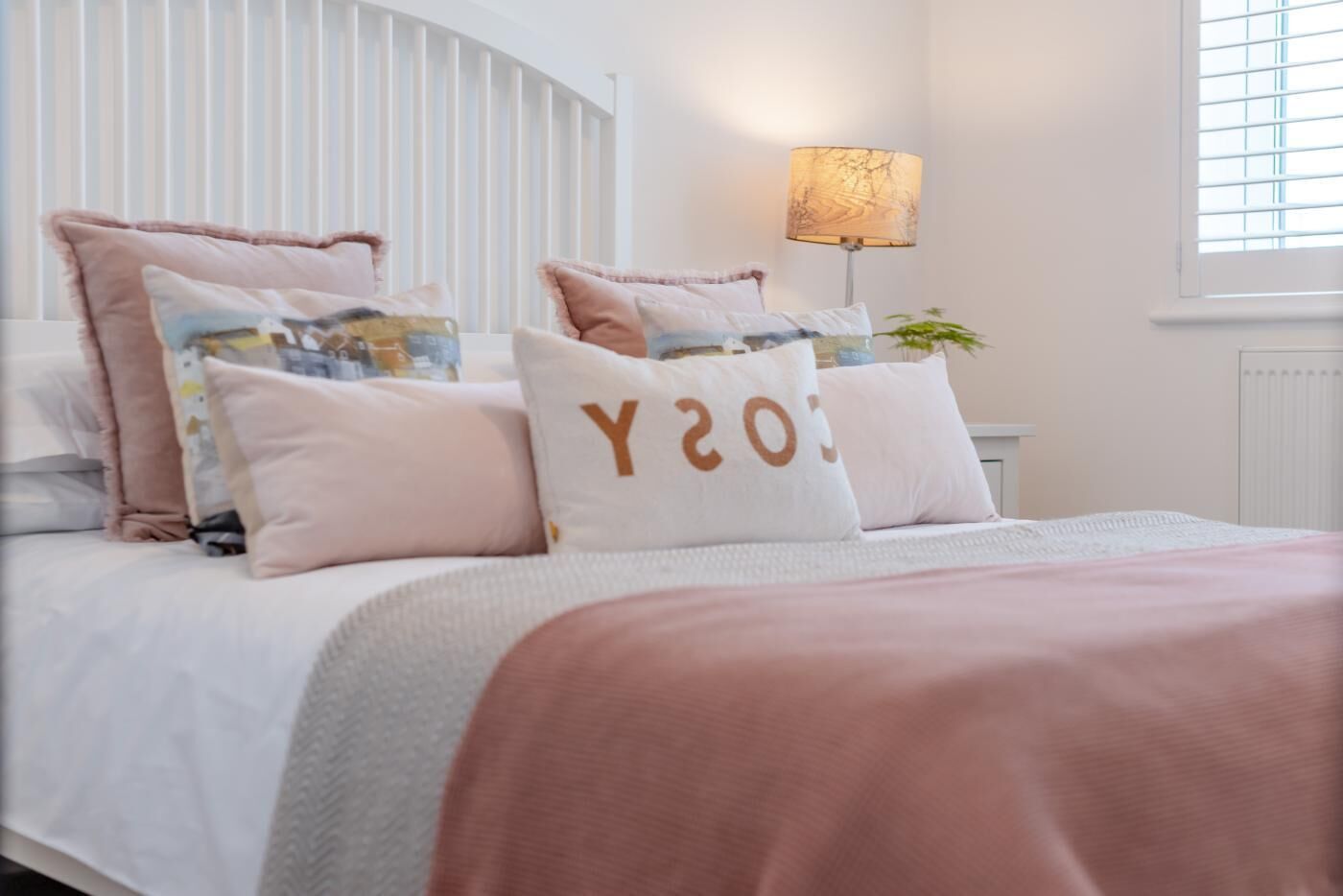 A neatly made bed with multiple pillows and a bedside lamp.