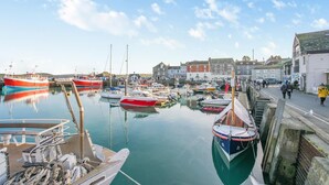 Un port où des bateaux sont amarrés, une promenade le long de l’eau et des bâtiments en arrière-plan.