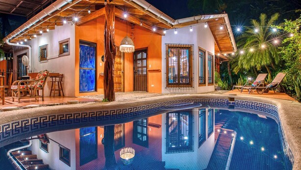 Ein Haus mit Swimmingpool, Holzterrasse und Sitzgelegenheit im Freien.