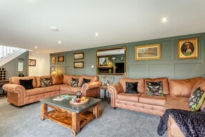 A living room with two leather sofas, a coffee table, and a piano. - 6 Bed in Holsworthy (oc-s41430) (Holsworthy Hamlets)