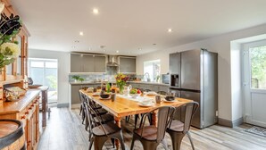 Une cuisine moderne avec une table à manger en bois, des chaises et un réfrigérateur.