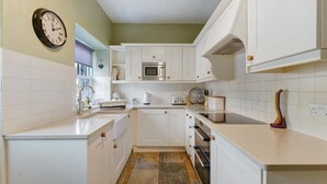 A kitchen with white cabinets, a microwave, a toaster, and a clock on the wall. - 2 Bed in Skelwith Bridge (oc-lr128) (Skelwith)