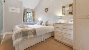 A bedroom with a bed, a dresser, a mirror, a heart-shaped decoration, and a window with curtains. - 2 Bed in Skelwith Bridge (oc-lr128) (Skelwith)