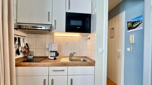 A compact kitchen with a microwave, coffee maker, and stainless steel sink. - Gemutliches Studio in Sellin mit Balkon (Sellin)