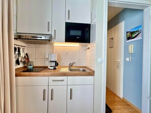 A compact kitchen with a microwave, coffee maker, and stainless steel sink. - Gemutliches Studio in Sellin mit Balkon (Sellin)