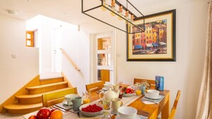 Zona pranzo con tavolo apparecchiato per la colazione, una scala e un quadro appeso al muro.