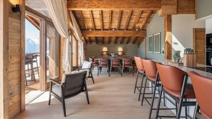 Een ruime eetruimte met houten balken, een grote tafel en stoelen.