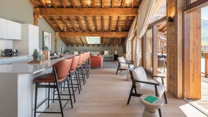 Een moderne keuken met een bar, houten balken in het plafond en uitzicht op het omliggende landschap.