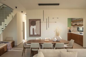 A modern interior with a dining area, kitchen, and staircase. - Thenad Villas - Villa Nadia Heated Pool, by Estia (Skaleta)