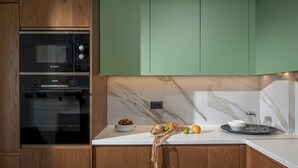 Una cocina con horno Bosch, armarios de madera, salpicadero de mármol y una encimera con frutero y cristalería.