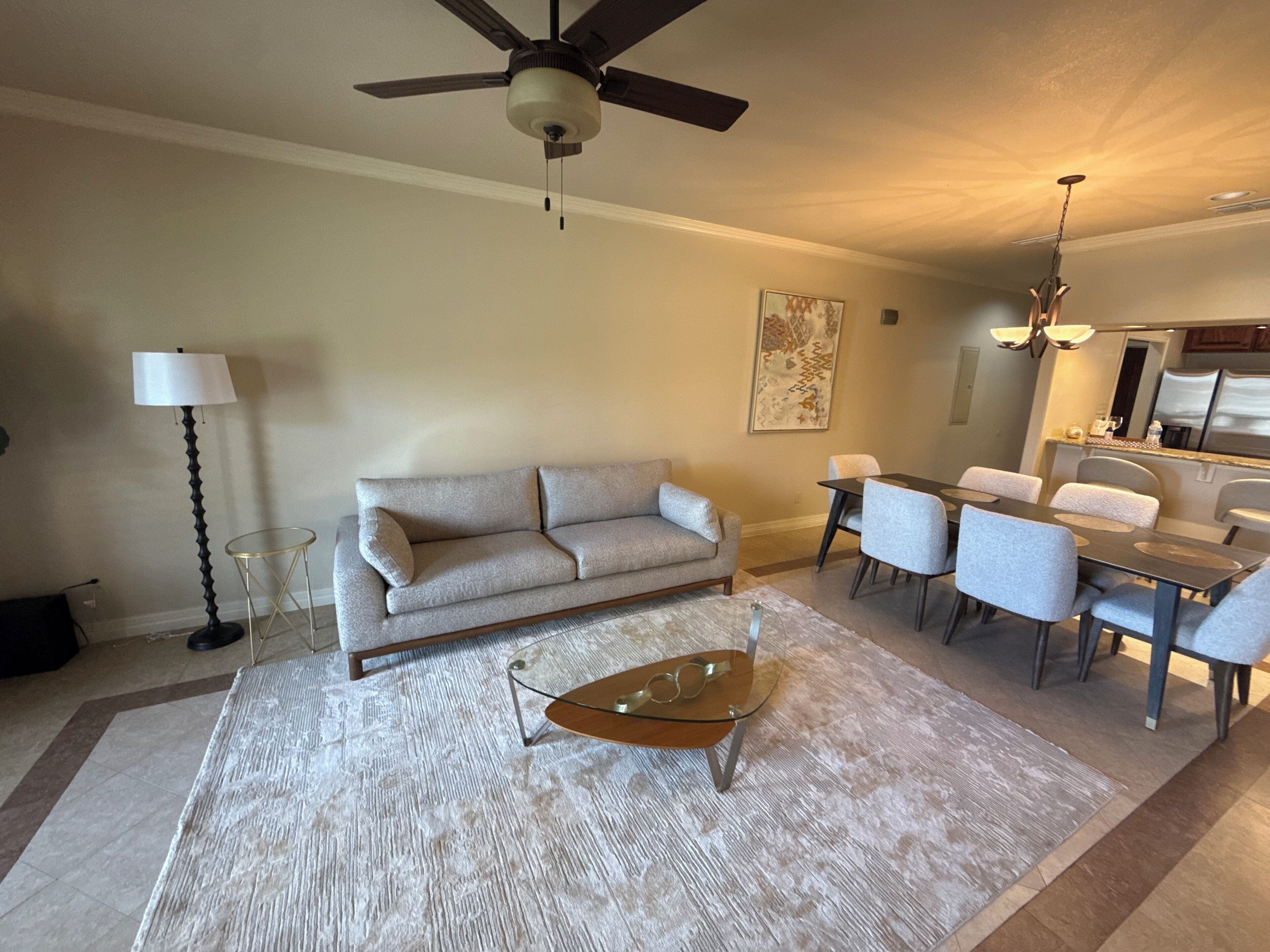 Un salon comprenant un canapé, une table basse, une table à manger, des chaises et un ventilateur de plafond.