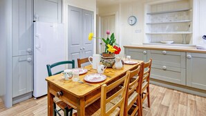 Une cuisine moderne avec des meubles blancs, une table à manger en bois et une horloge au mur.