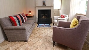 Un salon avec une cheminée, un canapé, un fauteuil et un tapis.
