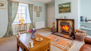 Una sala de estar acogedora con chimenea, una mesa de comedor con un florero y un sofá cómodo.