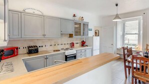 Una cocina moderna con gabinetes grises, una isla de madera, un microondas rojo y una estufa.