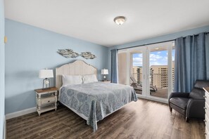 Slaapkamer met een bed, nachtkastjes, een dressoir, een stoel, een balkon met uitzicht en een plafondlamp.