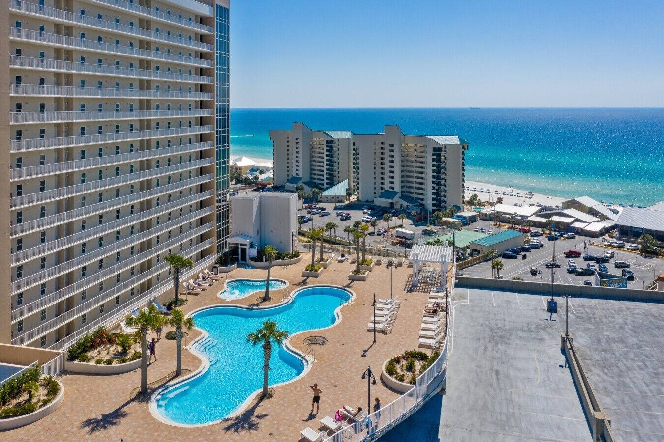 A hotel with a pool, beach view, and multiple buildings.