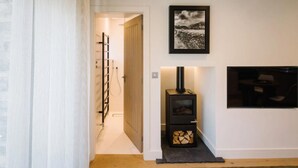 A hallway with a wooden door, a black wood-burning stove, and a framed picture on the wall. - 1 Bed in Windermere (oc-lr229) (Windermere)
