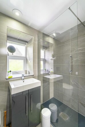 A modern bathroom with two sinks, a large mirror, a shower enclosure, and a window. - 3 Bed in Ambleside (oc-lr012) (Ambleside)