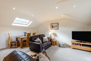 A modern loft-style living room with a high ceiling, a dining area, and a flat-screen TV. - 2 Bed in Windermere (oc-lr001) (Windermere)