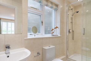 A bathroom with a sink, toilet, shower, and a window with a decorative item. - 2 Bed in Windermere (oc-lr001) (Windermere)