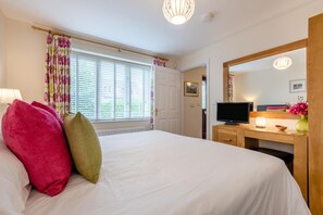 A hotel room with a bed, a television, a desk with a lamp, and a window with curtains. - 2 Bed in Windermere (oc-lr001) (Windermere)