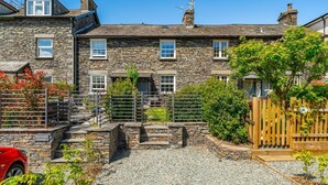 A stone cottage with a gravel driveway, wooden gates, and a red car parked outside. - 2 Bed in Ambleside (oc-lr002) (Ambleside)