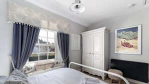 A bedroom with a bed, a window with curtains, a white wardrobe, a radiator, and a painting on the wall. - 2 Bed in Ambleside (oc-lr002) (Ambleside)