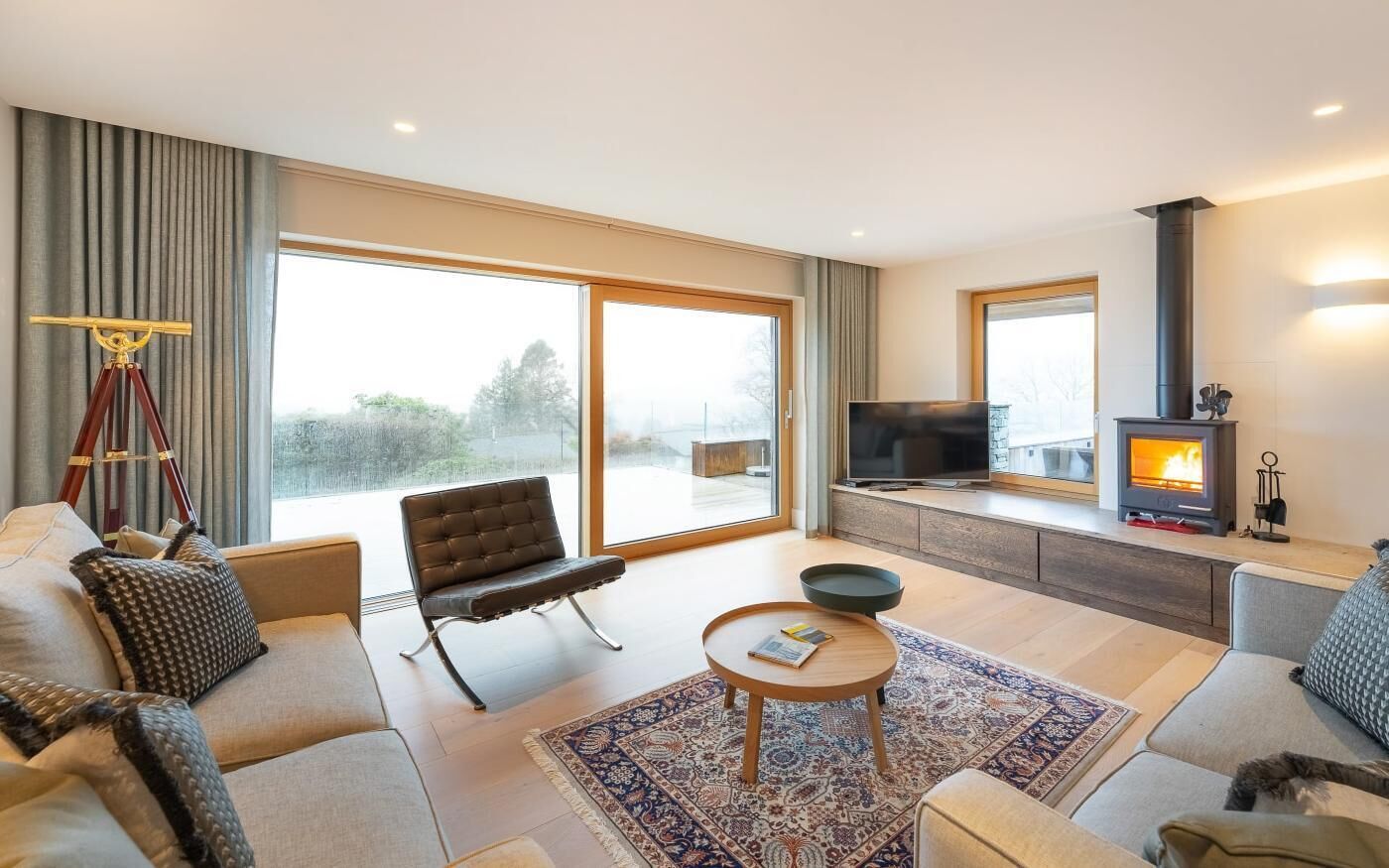A modern living room with a sofa, armchair, coffee table, and a fireplace.