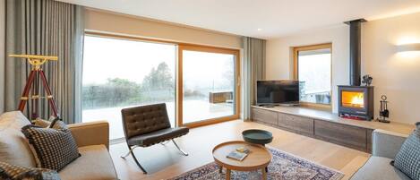 A modern living room with a sofa, armchair, coffee table, and a fireplace.