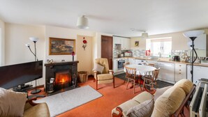 A living room with a fireplace, a dining area, and a kitchen with modern appliances. - 3 Bed in Hawkshead (oc-lr238) (Hawkshead Hill)