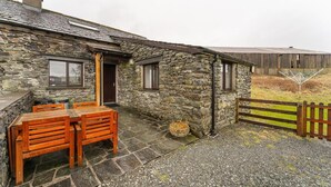 A stone building with a wooden table and chairs outside. - 3 Bed in Hawkshead (oc-lr238) (Hawkshead Hill)
