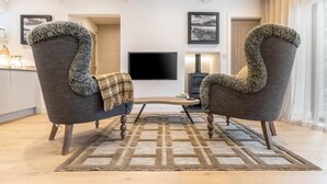 A modern living room with two armchairs, a coffee table, a flat-screen TV, and a fireplace. - 1 Bed in Windermere (oc-lr232) (Windermere)