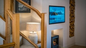 A staircase with wooden railings, a wall-mounted lamp, a framed picture, a fireplace, and a wall-mounted television. - 3 Bed in Windermere (oc-lr235) (Windermere)