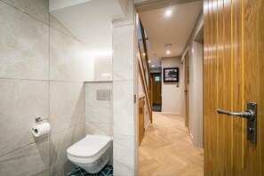 A modern bathroom with a toilet, shower, and wooden door. - 3 Bed in Windermere (oc-lr235) (Windermere)