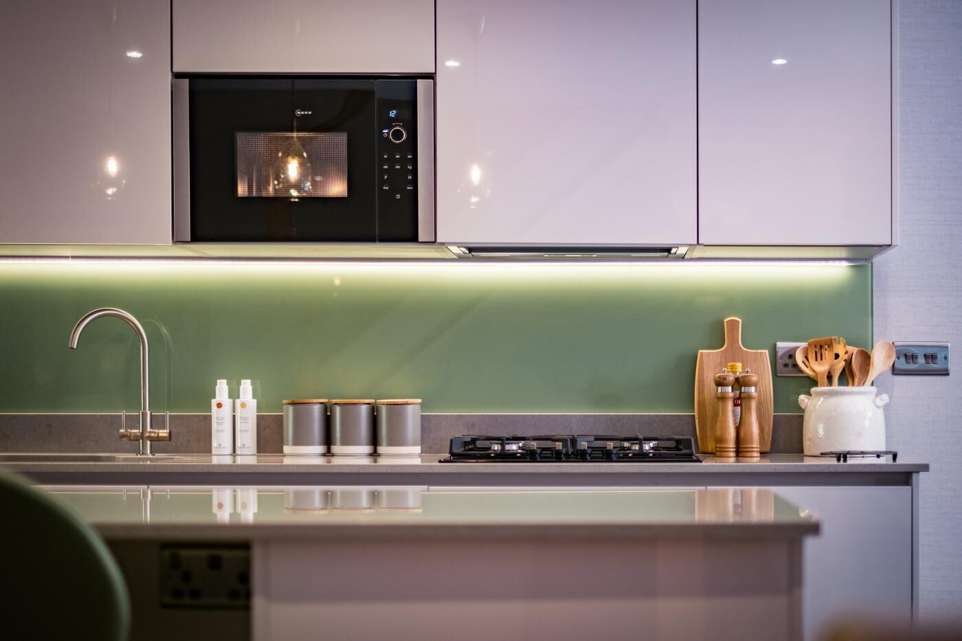 Une cuisine moderne équipée d’un four à micro-ondes encastré, d’une cuisinière à gaz et d’appareils électroménagers en acier inoxydable.