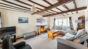 Ein Wohnzimmer mit Kamin, Sofas, einem Fernseher und einer Holzzahlendecke.