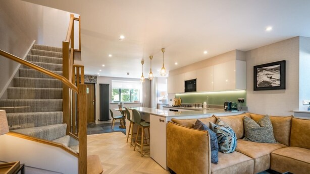 A modern interior with a staircase, a sofa, a dining area, and a kitchen. - 3 Bed in Windermere (oc-lr228) (Windermere)